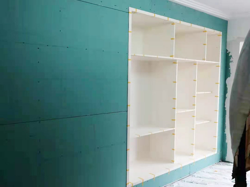 客廳定制柜體安裝：用墊布點好地板，先從靠墻的一端寬側板開始組裝，將寬側板平放于地面上（離后墻面保持700mm間隔）。首先將填好的三合一膠塞的板件，平放在墊布上，檢查孔距與圖紙相符，并裝上三合一單連桿。然后將固層釘上木塞，固定于寬側板上面，頂板大柄孔朝上，其余固層都朝下，腳線大柄孔朝內（中間固層與L架高度一致，即底板到固層內空為960mm，現場打層板孔）。放上側板，釘上木塞，木塞要求連通兩邊的固層。在第二個柜固層上面裝好雙連桿，留意雙連桿上面大柄只能鎖住一半，即90°。當兩件固層與側板固定后再同時擰緊大柄。裝第三個柜時重復第二個柜的安裝步驟。